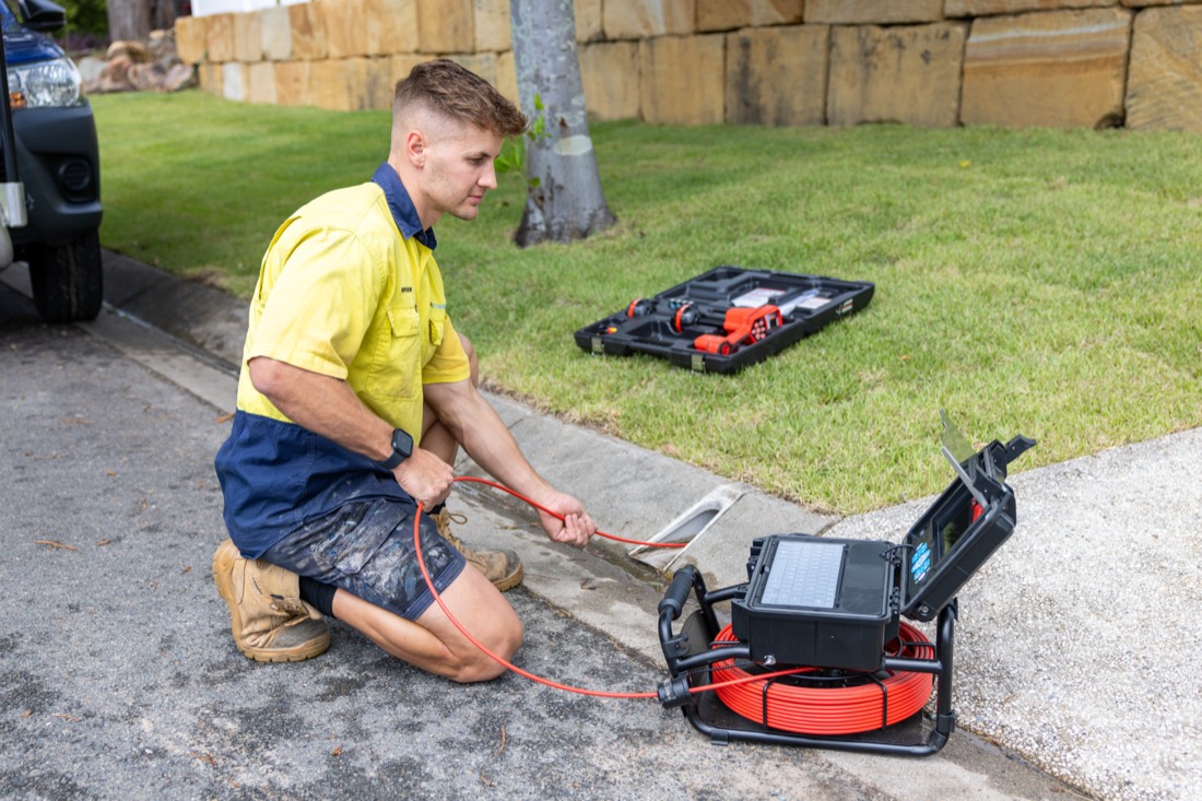 Senco Plumbing technician running a CCTV drain camera reel and monitor to inspect an underground drain for blockages and pipe damage in Brisbane