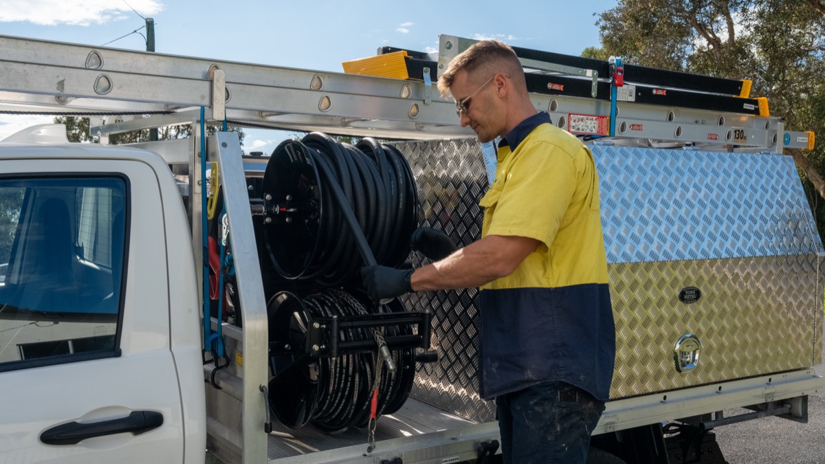 Senco Plumbing plumber with the high-pressure jetting hose reels at the branded Senco ute in Northgate, Brisbane